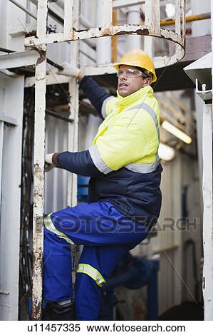 Stock Photography - Worker climbing ladder on oil rig. Fotosearch