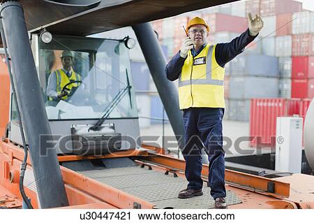 Worker directing machinery on site View Large Photo Image Stock Image - Worker directing machinery on site. Fotosearch