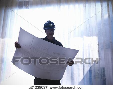 Worker examining blueprints View Large Photo Image Stock Photo - Worker examining blueprints. Fotosearch