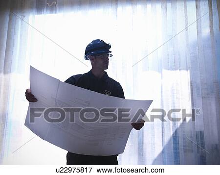 Stock Photo - Worker examining blueprints. Fotosearch