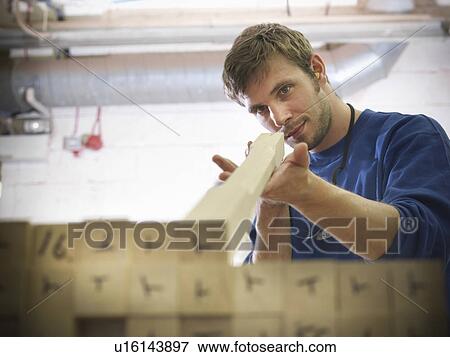 Stock Photo - Worker examining wood in joinery. Fotosearch