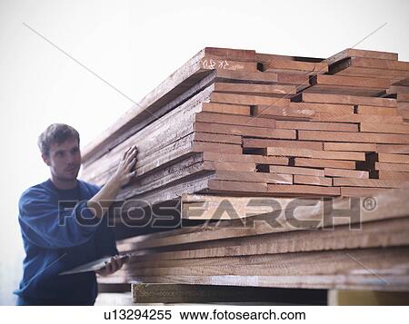Stock Photography - Worker examining wood in joinery. Fotosearch