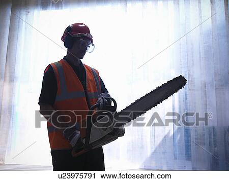 Stock Image - Worker holding chainsaw. Fotosearch