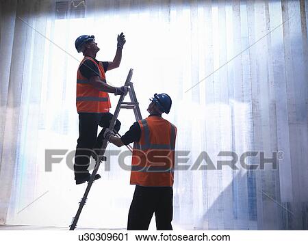Worker holding ladder for colleague View Large Photo Image Stock Image - Worker holding ladder for colleague. Fotosearch