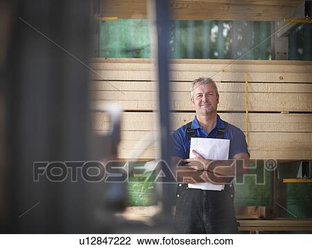 Worker holding papers in joinery View Large Photo Image Stock Image - Worker holding papers in joinery. Fotosearch
