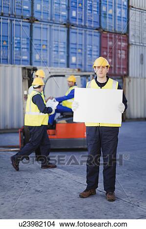 Worker holding sheet in shipping yard View Large Photo Image Picture - Worker holding sheet in shipping yard. Fotosearch