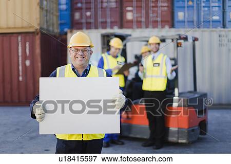 Worker holding sheet in shipping yard View Large Photo Image Stock Photo - Worker holding sheet in shipping yard. Fotosearch