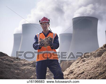 Stock Image - Worker holding willow biomass fuel. Fotosearch
