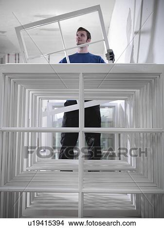 Picture - Worker holding window frames in joinery. Fotosearch