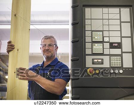 Stock Image - Worker holding wood in joinery. Fotosearch