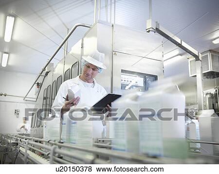 Stock Photo - Worker inspecting goat's milk in dairy. Fotosearch