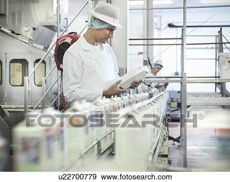 Stock Photo - Worker inspecting goat's milk in dairy. Fotosearch