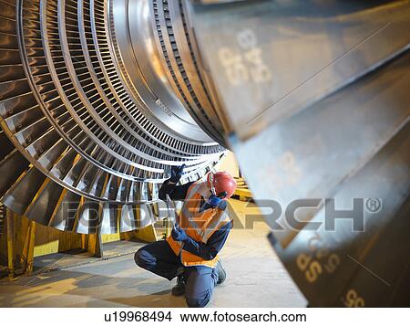 Worker inspects turbine in power station View Large Photo Image Picture - Worker inspects turbine in power station. Fotosearch