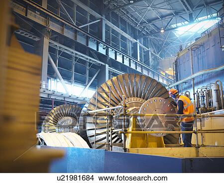 Picture - Worker inspects turbine in power station. Fotosearch