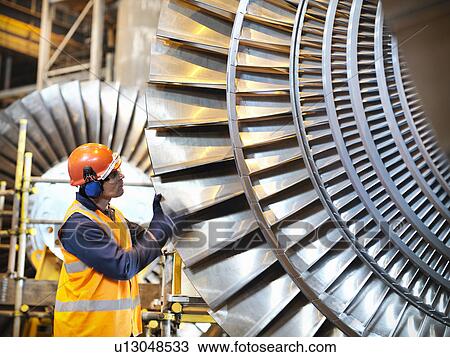 Worker inspects turbine in power station View Large Photo Image Stock Image - Worker inspects turbine in power station. Fotosearch