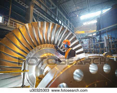 Worker inspects turbine in power station View Large Photo Image Stock Image - Worker inspects turbine in power station. Fotosearch