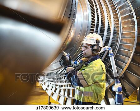 Worker inspects turbine in power station View Large Photo Image Stock Photo - Worker inspects turbine in power station. Fotosearch