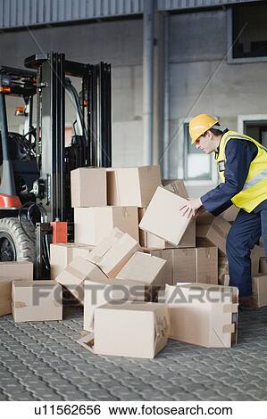 Stock Photograph - Worker loading boxes onto forklift. Fotosearch