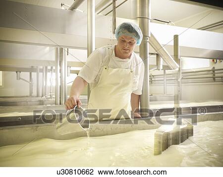 Stock Image - Worker mixing cheese in factory. Fotosearch