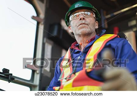 Stock Image - Worker operating machinery on oil rig. Fotosearch