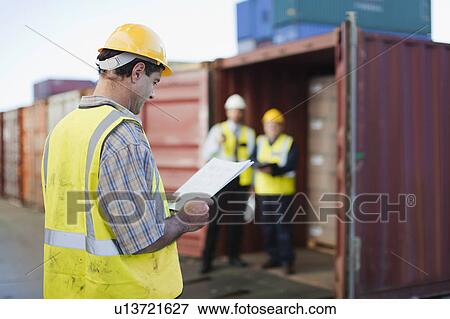 Worker reading in shipping yard View Large Photo Image Stock Photo - Worker reading in shipping yard. Fotosearch
