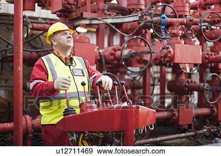 Stock Photo - Worker sitting in chair on oil rig. Fotosearch