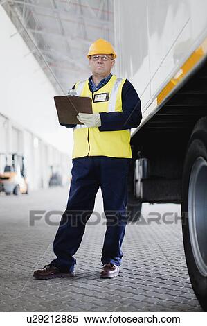 Stock Photography - Worker standing by truck in warehouse. Fotosearch