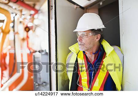 Stock Photo - Worker standing in doorway on oil rig. Fotosearch