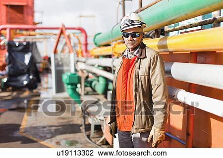 Worker standing on oil rig View Large Photo Image Stock Image - Worker standing on oil rig. Fotosearch