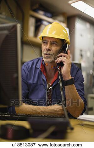 Stock Photo - Worker talking on phone in office. Fotosearch