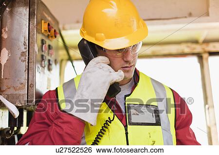 Stock Photograph - Worker talking on phone on oil rig. Fotosearch