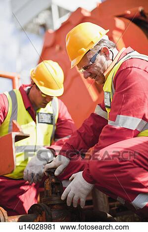 Worker turning wheel on oil rig View Large Photo Image Stock Image - Worker turning wheel on oil rig. Fotosearch