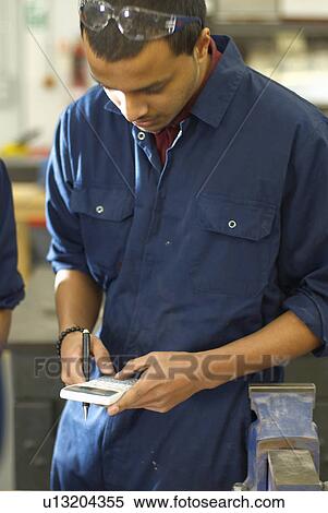 Stock Photography - Worker using calculator in factory. Fotosearch