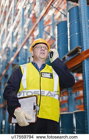 Picture - Worker using cell phone in warehouse. Fotosearch
