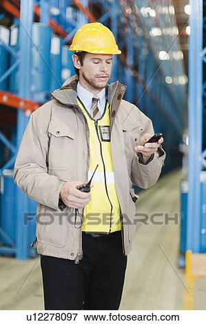 Worker using cell phone in warehouse View Large Photo Image Stock Photo - Worker using cell phone in warehouse. Fotosearch