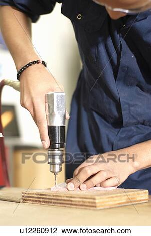 Stock Image - Worker using drill in factory. Fotosearch