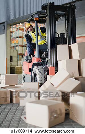 Worker using forklift to pick up boxes View Large Photo Image Picture - Worker using forklift to pick up boxes. Fotosearch