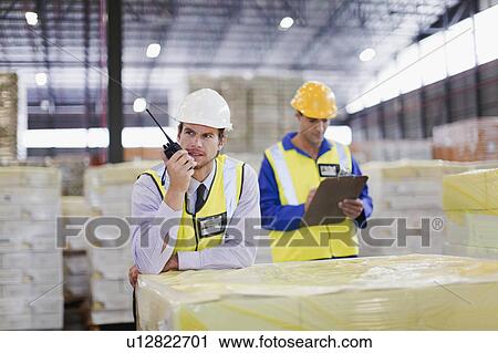 Worker using walkie talkie in warehouse View Large Photo Image Stock Image - Worker using walkie talkie in warehouse. Fotosearch