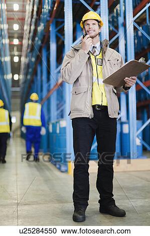 Worker using walkie talkie in warehouse View Large Photo Image Stock Image - Worker using walkie talkie in warehouse. Fotosearch
