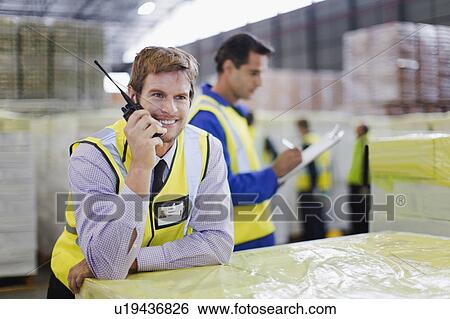 Worker using walkie talkie in warehouse View Large Photo Image Stock Photograph - Worker using walkie talkie in warehouse. Fotosearch
