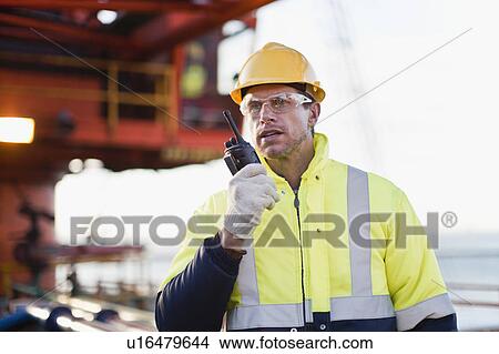 Worker using walkie talkie on oil rig View Large Photo Image Picture - Worker using walkie talkie on oil rig. Fotosearch