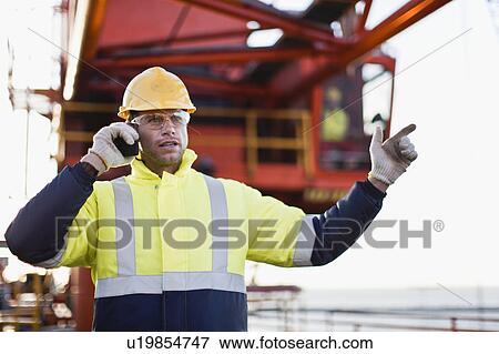 Stock Photo - Worker using walkie talkie on oil rig. Fotosearch
