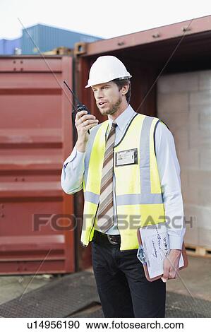Stock Image - Worker using walkie talkie on site. Fotosearch