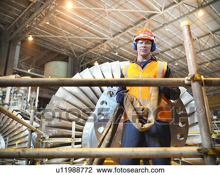 Stock Image - Worker with turbine in power station. Fotosearch