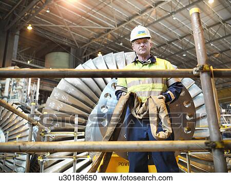 Stock Image - Worker with turbine in power station. Fotosearch