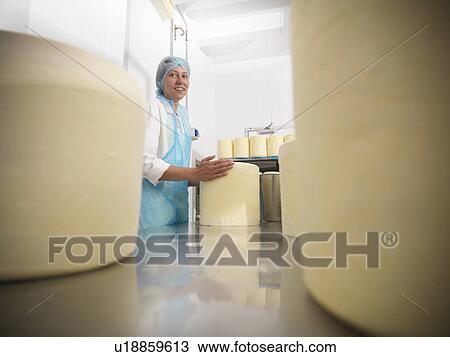 Stock Image - Worker wrapping cheese in factory. Fotosearch