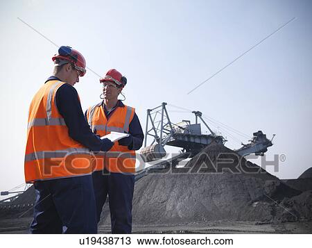 Stock Image - Workers at coal storage facility. Fotosearch