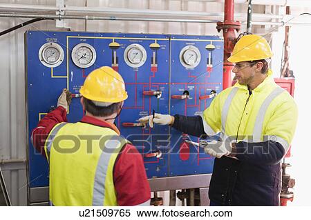 Stock Photography - Workers checking gauges on oil rig. Fotosearch