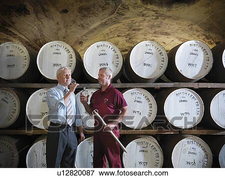 Workers checking whisky in distillery View Large Photo Image Stock Photo - Workers checking whisky in distillery. Fotosearch