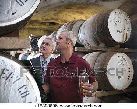Stock Photograph - Workers checking whisky in distillery. Fotosearch